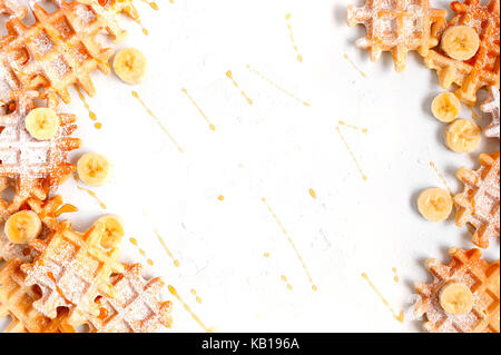 Background with many small waffles with banana and honey on the white table Stock Photo