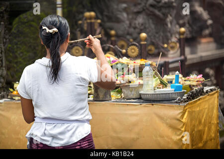 woman praying god in Ubud, Bali, Indonesia, every morning women bring flowers and incense to their gods Stock Photo