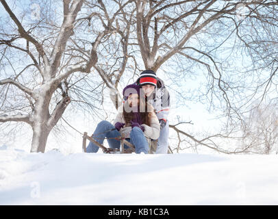 Young couple sledding, couple on sled in winter park Stock Photo
