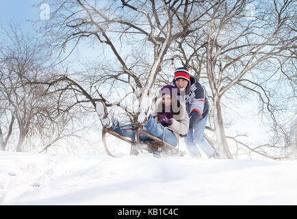 couple on sledge having fun in snow Stock Photo