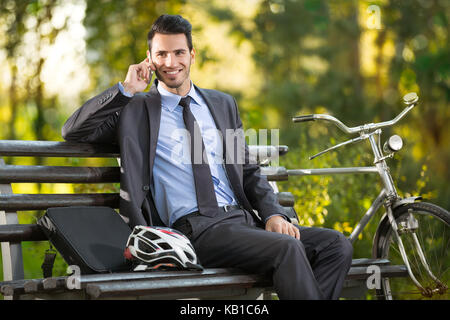 young man with his bicycle talking and resting in park Stock Photo