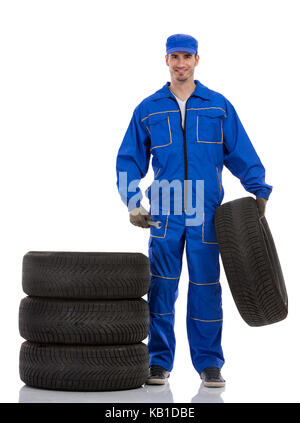 young car mechanic holding car tires on white background Stock Photo