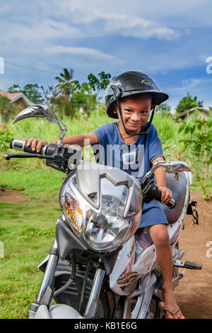 A four-year old Filipino boy sits on a motorcycle pretending to ride it in Ormoc City, Leyte Island, Philippines. Stock Photo