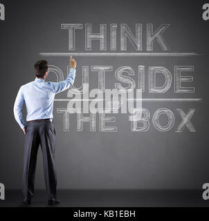 businessman writing "think outside the box" on wall, back view Stock Photo