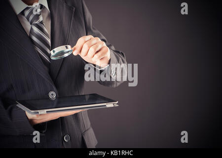 Businessman holding magnifying glass and digital tablet concept Stock Photo