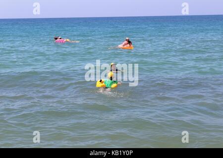 July, 2017 - Vacationers with inflatable mattresses swim in the sea at Cleopatra Beach (Alanya, Turkey). Stock Photo
