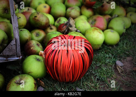 Red weaved apple made from dried apple peels with green apples in background found at a craft fair Stock Photo