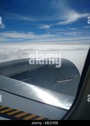 Skies the limit from the window of a jet airliner at altitude. Clear blue skies and wispy clouds seen from the clean window of a modern a aircraft. Stock Photo