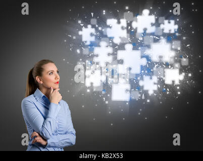 Thinking businesswoman looking at clouds of shining puzzle pieces Stock Photo