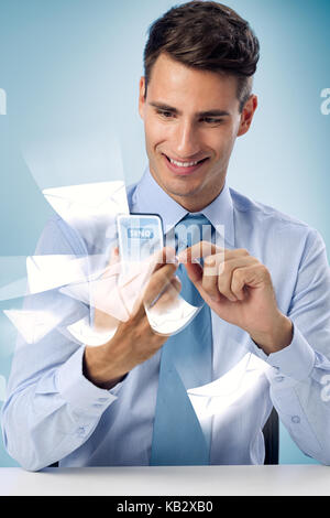 Smiling man using futuristic phone sending mail Stock Photo