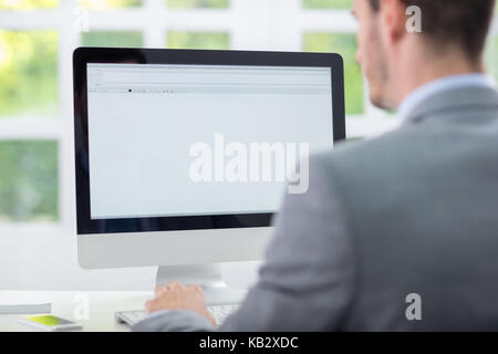 Business man sitting front of empty monitor, back view Stock Photo
