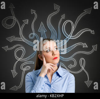 Confused, young businesswoman with many arrows pointed in different directions Stock Photo
