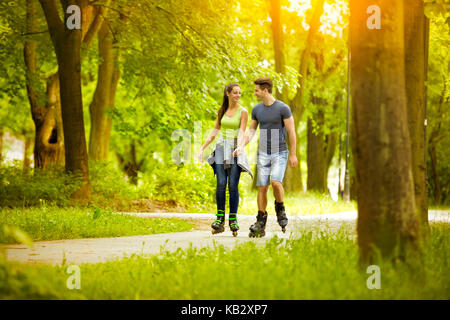 Happy couple wearing in line skates in park Stock Photo