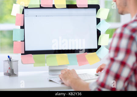 Man working on computer with sticky notes, back view Stock Photo