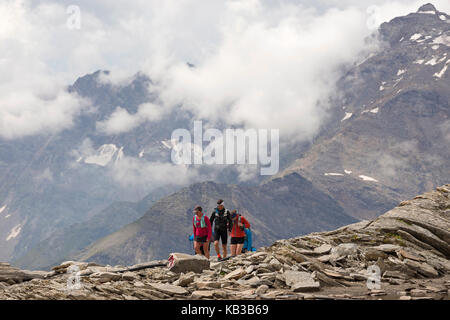 MORO PASS NEAR MACUGNAGA, ITALY - JULY 2017; Group of hikers walking on the rocks. Stock Photo