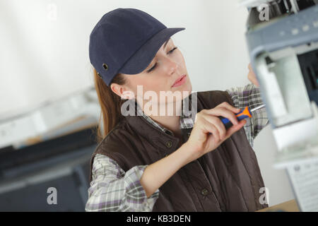 female technician using a screwdriver for fixing printer Stock Photo