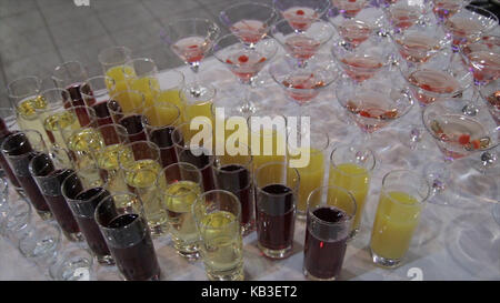 Champagne in glasses with fresh cherry on table and party background. Top View Of Glasses With Different Alcohol Drinks On A Table At Wedding. Pyramid Of Red Blue Champagne Martini Glasses At Event. Tier Of Martini Glass With Cherries. Juices Stock Photo