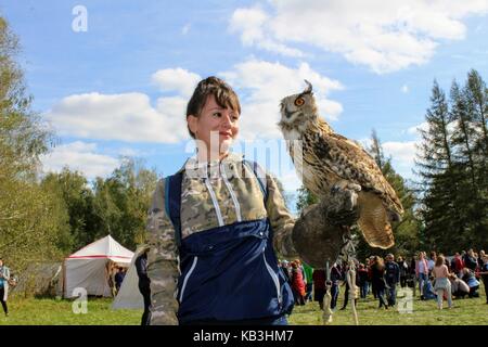 The International Military and Historical Festival 'Kulikovo Field': a woman with a falcon glove holds an owl on her outstretched hand. Stock Photo