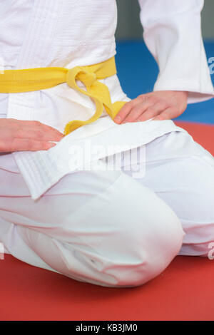 boy stands in white kimono with a yellow belt Stock Photo