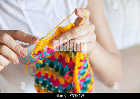 A woman knits a colored cloth. Hands close-up. Stock Photo
