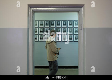 Tourist passing by portraits of prisoners at the Auschwitz WWII Nazi concentration camp museum, Poland Stock Photo