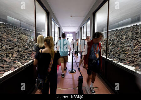 Tourists looking at piles of shoes belonging to prisoners at Auschwitz WWII Nazi concentration camp museum, Poland Stock Photo