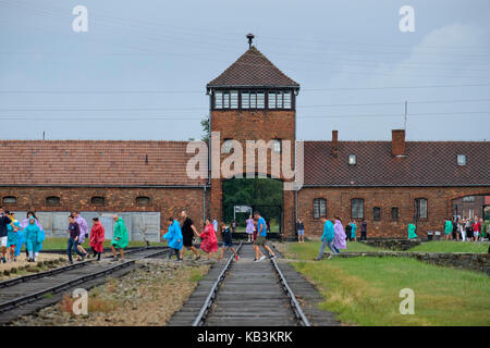 Tourists passing in front of the entrance gate to the Auschwitz II BIrkenau WWII Nazi concentration camp, Poland Stock Photo