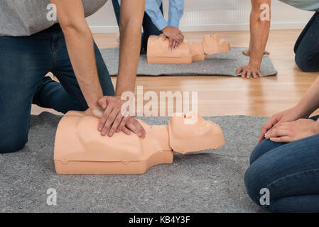 Students Practicing Cpr Chest Compression On Dummy In Class Stock Photo