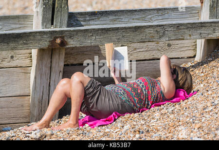 Woman laying on a beach reading a book. Stock Photo