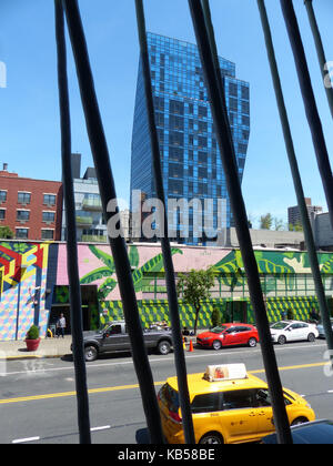 Delancey Street Blue Condominium, aka Blue Tower designed by Architect Bernard Tschumi,  photographed through parking garage on Essex Street with yellow cab passing by Stock Photo