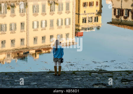 Young girl is making photographs of Florence buildings, reflected in the Arno river Stock Photo