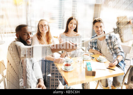 Positive friends using selfie stick Stock Photo