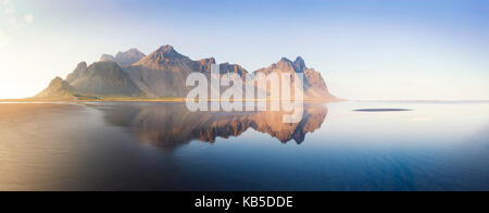 Panoramic view of Vestrahorn Mountain range reflecting in shallows of black volcanic beach, Stokksnes, South Iceland Stock Photo