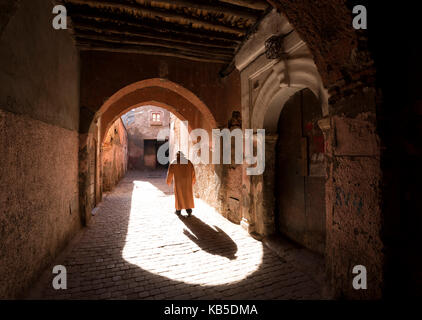 Local man dressed in traditional djellaba walking through archway in a street in the Kasbah, Marrakech, Morocco, North Africa Stock Photo