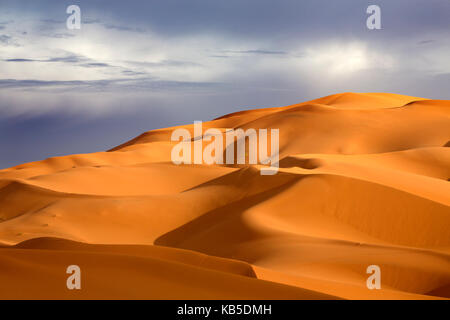 Orange sand dunes against stormy sky, Erg Chebbi sand sea, part of the Sahara Desert near Merzouga, Morocco, North Africa