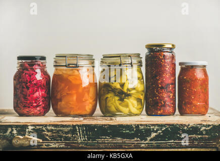 Autumn pickled colorful vegetables in jars placed in row Stock Photo