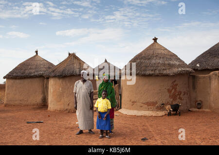 A young school girl with her parents outside their home in Tinguri, northern Ghana, West Africa, Africa Stock Photo