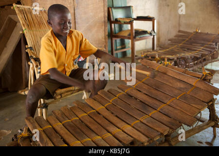 A school boy playing music on a large wooden xylophone at his primary school in Ghana, Africa Stock Photo