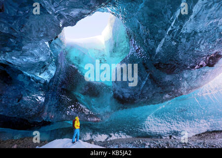Inside ice cave under the Vatnajokull Glacier, with cave guide looking up to hole in cave roof, near Jokulsarlon, South Iceland Stock Photo