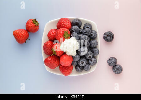Strawberries and Blueberries on pink and blue background Stock Photo