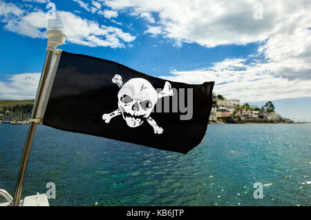 Jolly Roger flag on a boat in Dartmouth with Kingswear, Devon in the background. Seafood Coast. Pirates Stock Photo