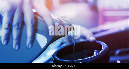 Mechanic pouring oil into car at repair garage Stock Photo