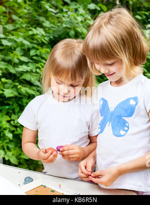 Two little girls are playing with  modelling clay outdoor Stock Photo