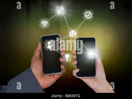 Digital composite of Hands holding phones with icons interface of internet of things Stock Photo