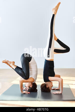 Two young women doing yoga asana crane pose. Bakasana Stock Photo