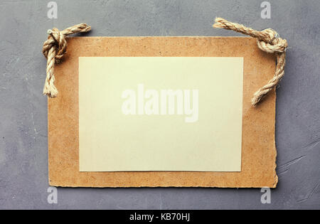 Wooden signboard with blank sheet of paper on gray textured wall Stock Photo