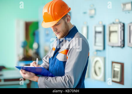 Portrait of young engineer taking notes at control room in factory Stock Photo