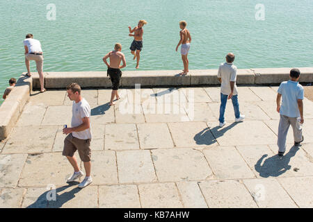Young blond boy jumping off the end of the Harbour Arm in Margate, Isle of Thanet, Kent. Stock Photo