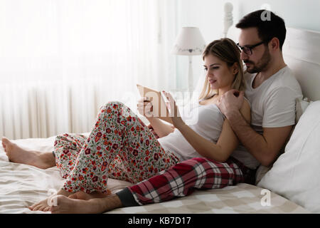 Young attractive couple using tablet in bedroom Stock Photo