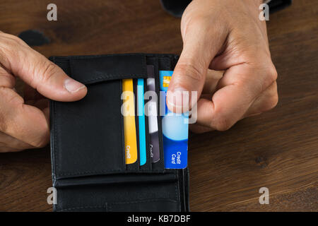 Cropped image of businessman showing credit card in wallet at desk Stock Photo